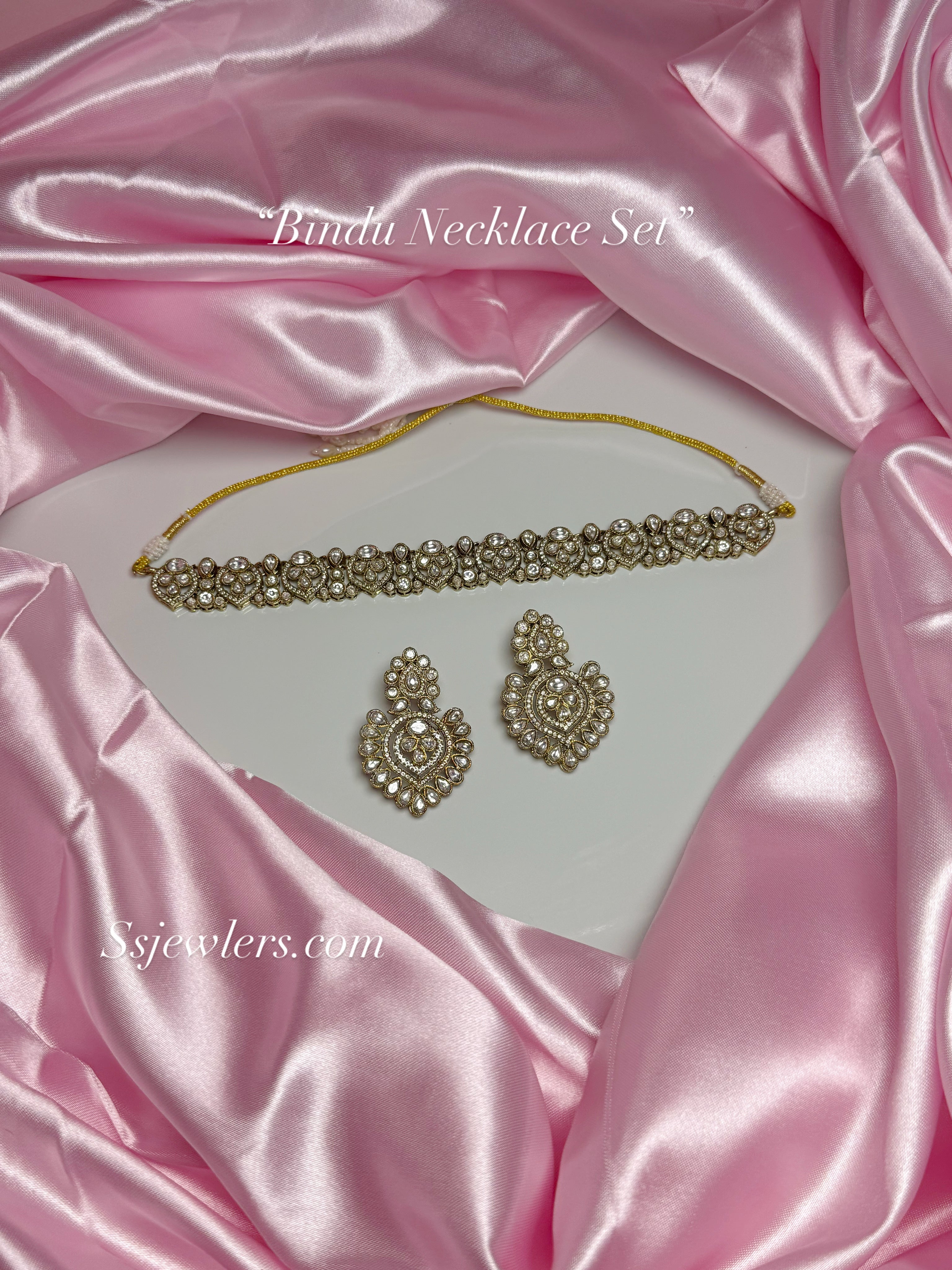 Bundu necklace set with earrings on pink satin fabric, featuring 'SsJewelers.com' branding.